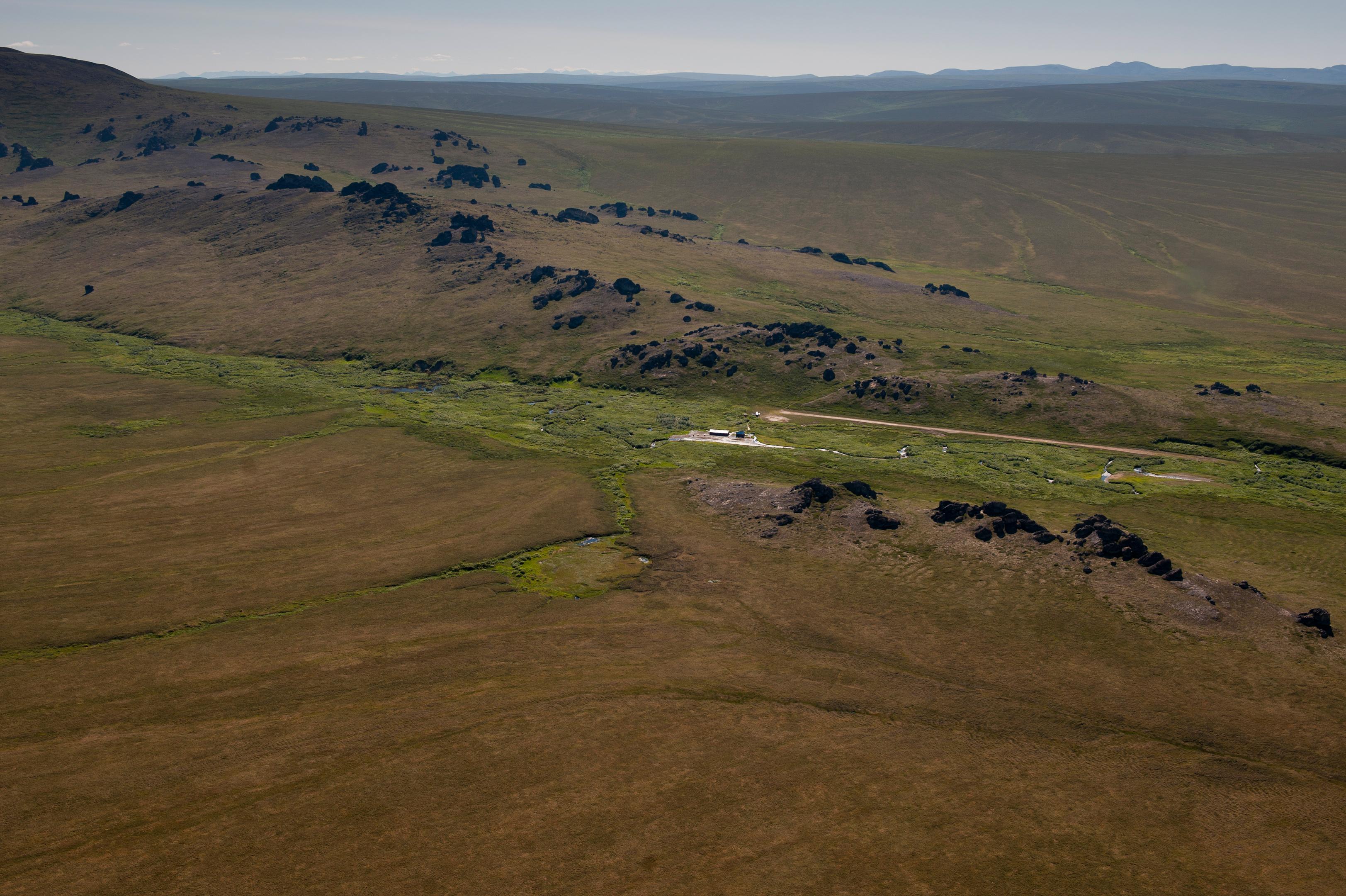 A vast expanse of undulating hills with granite spire jutting from the top.