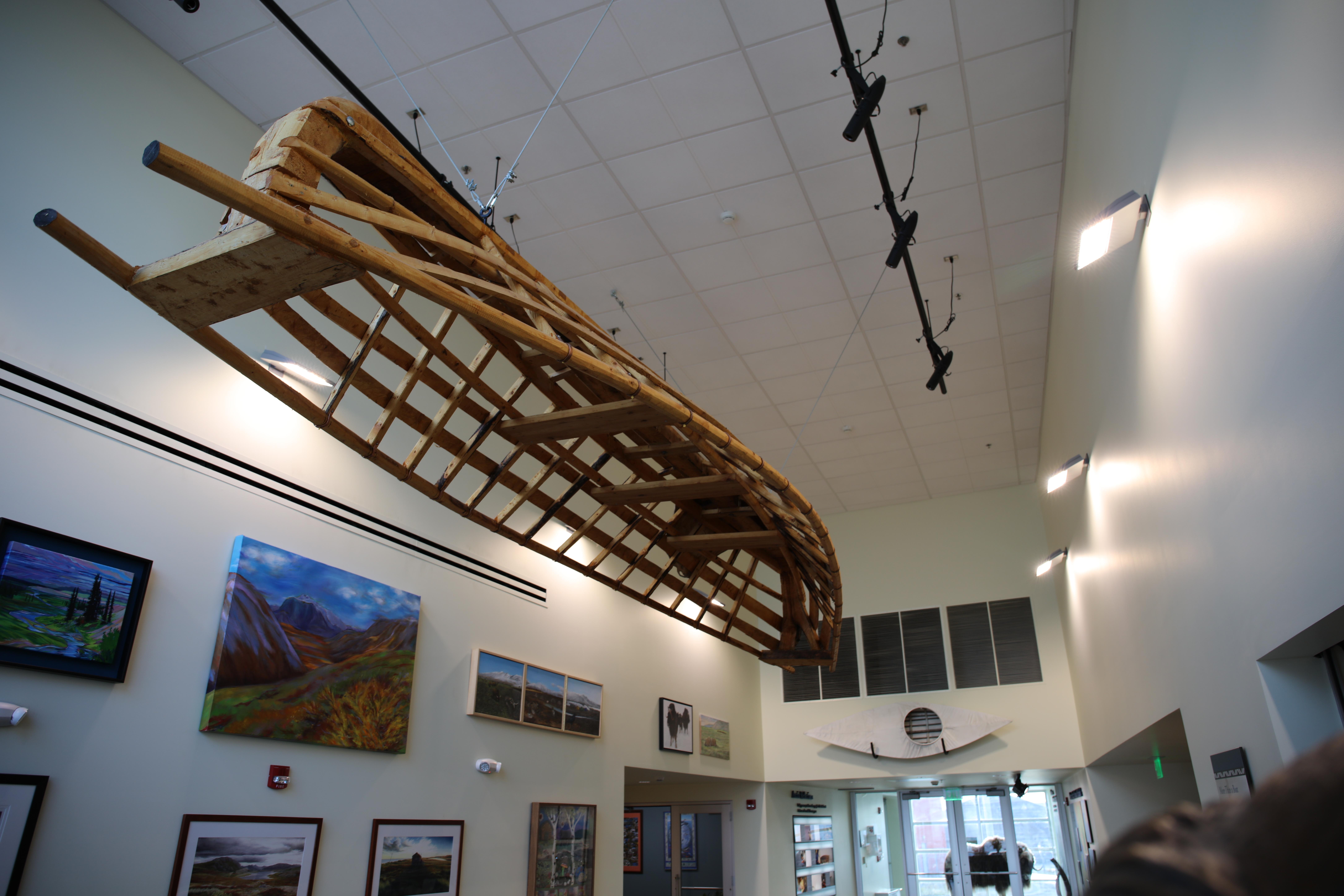 wooden boat frame hangs from vaulted ceiling in museum