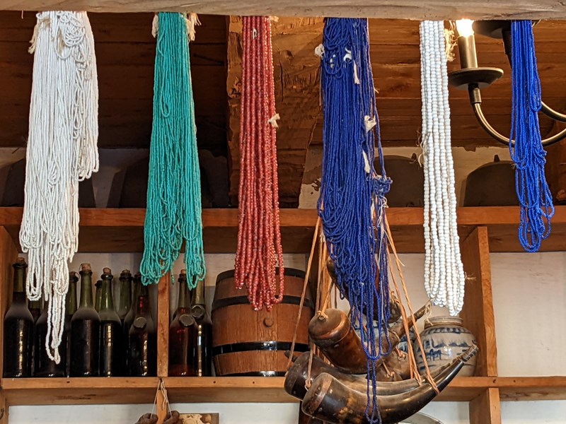 Beads in the Trade room bundles of glass trade beads tied together hang from a wooden rafter