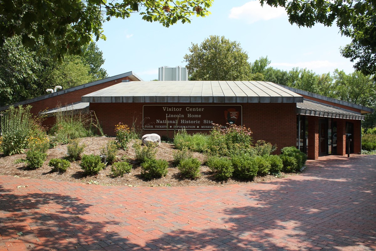 One story brick building with plants and shrubs. 