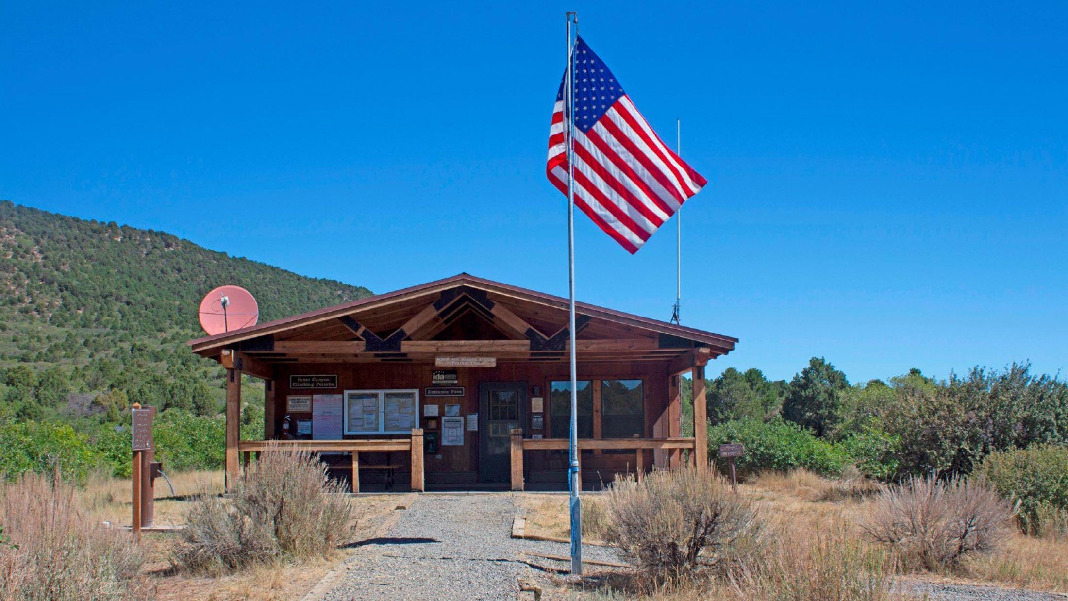 Wooden ranger station with a flag and a gravel pathway