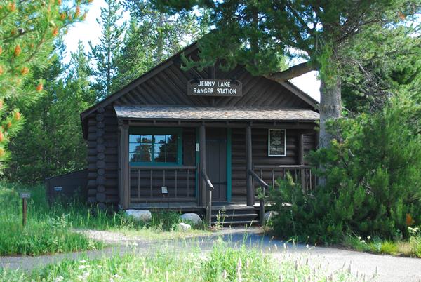 Brown painted log cabin with steps to a covered front porch