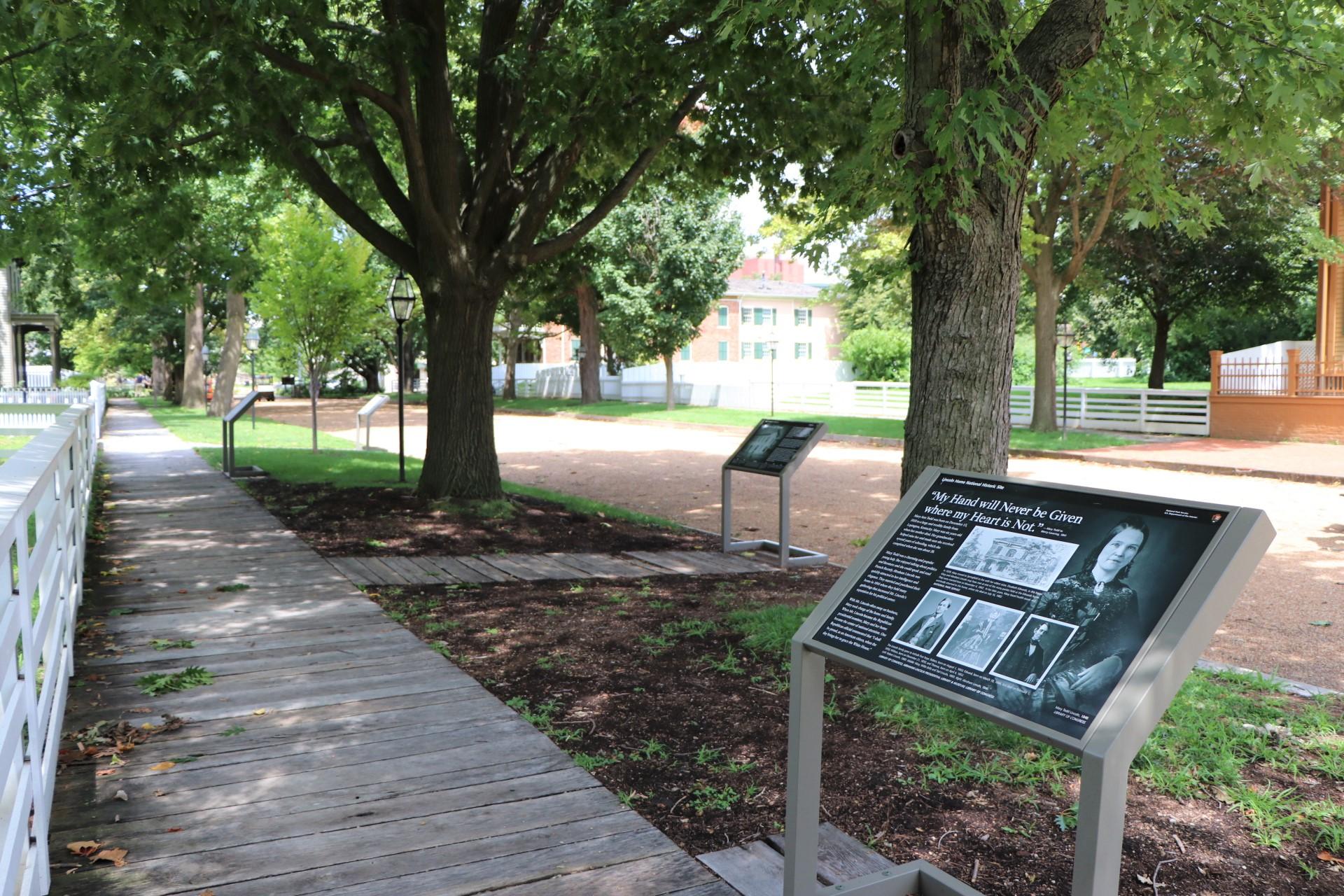 Graveled road with wooden boardwalks. Waist-high wayside exhibits next to boardwalks.