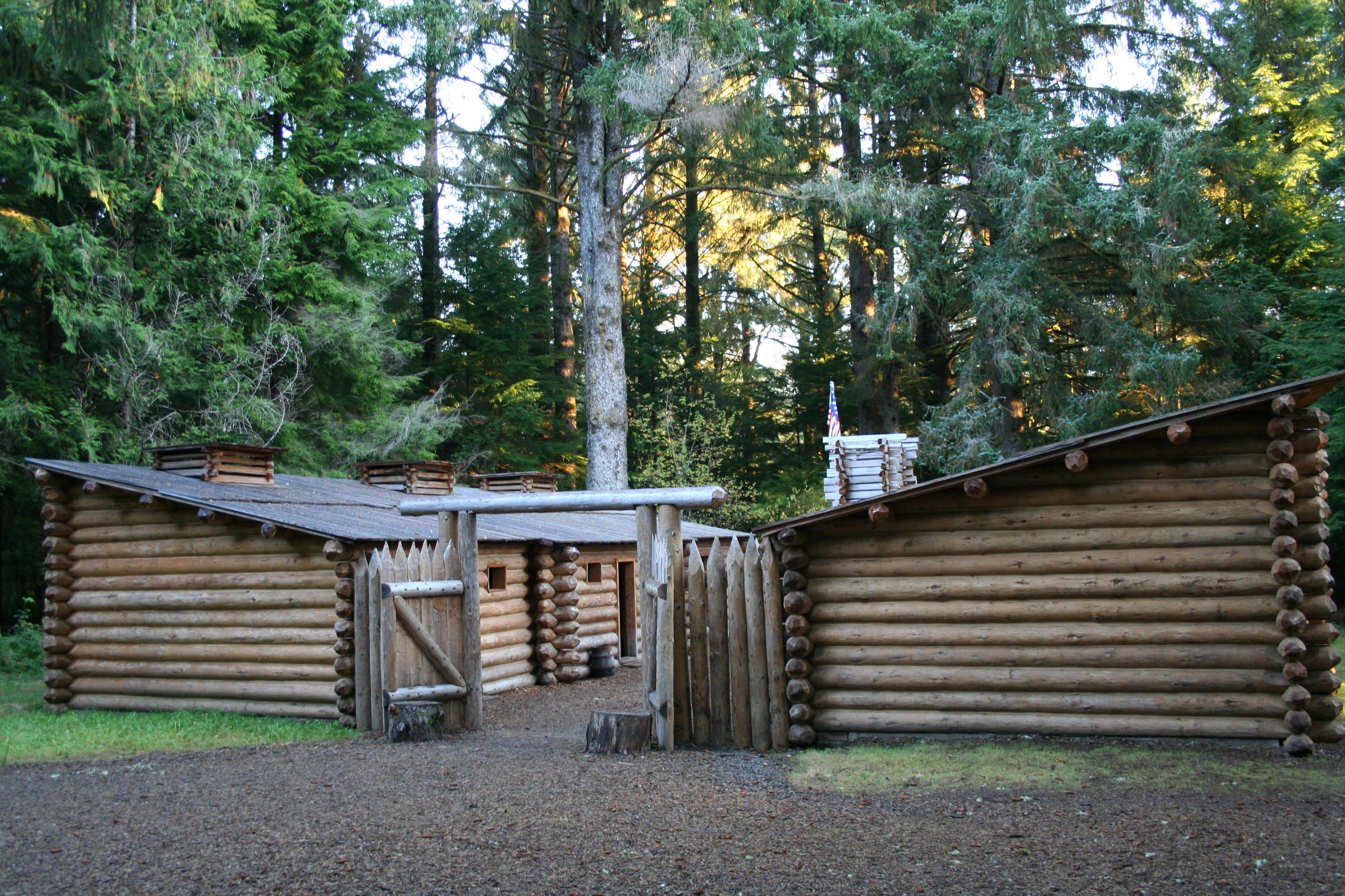 A fifty foot square wooden fort surrounded by tall trees in a forest.