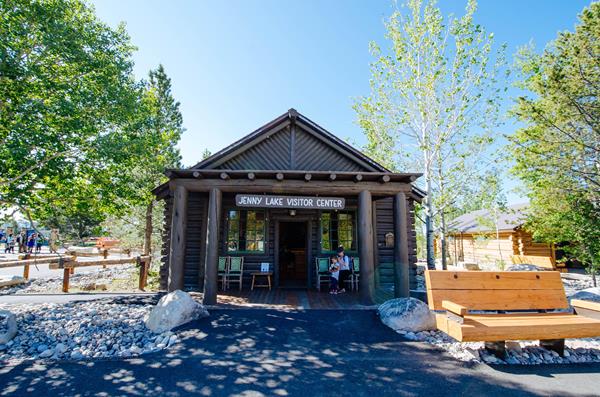 Log building with inviting covered porch. Information signs and benches are outside.