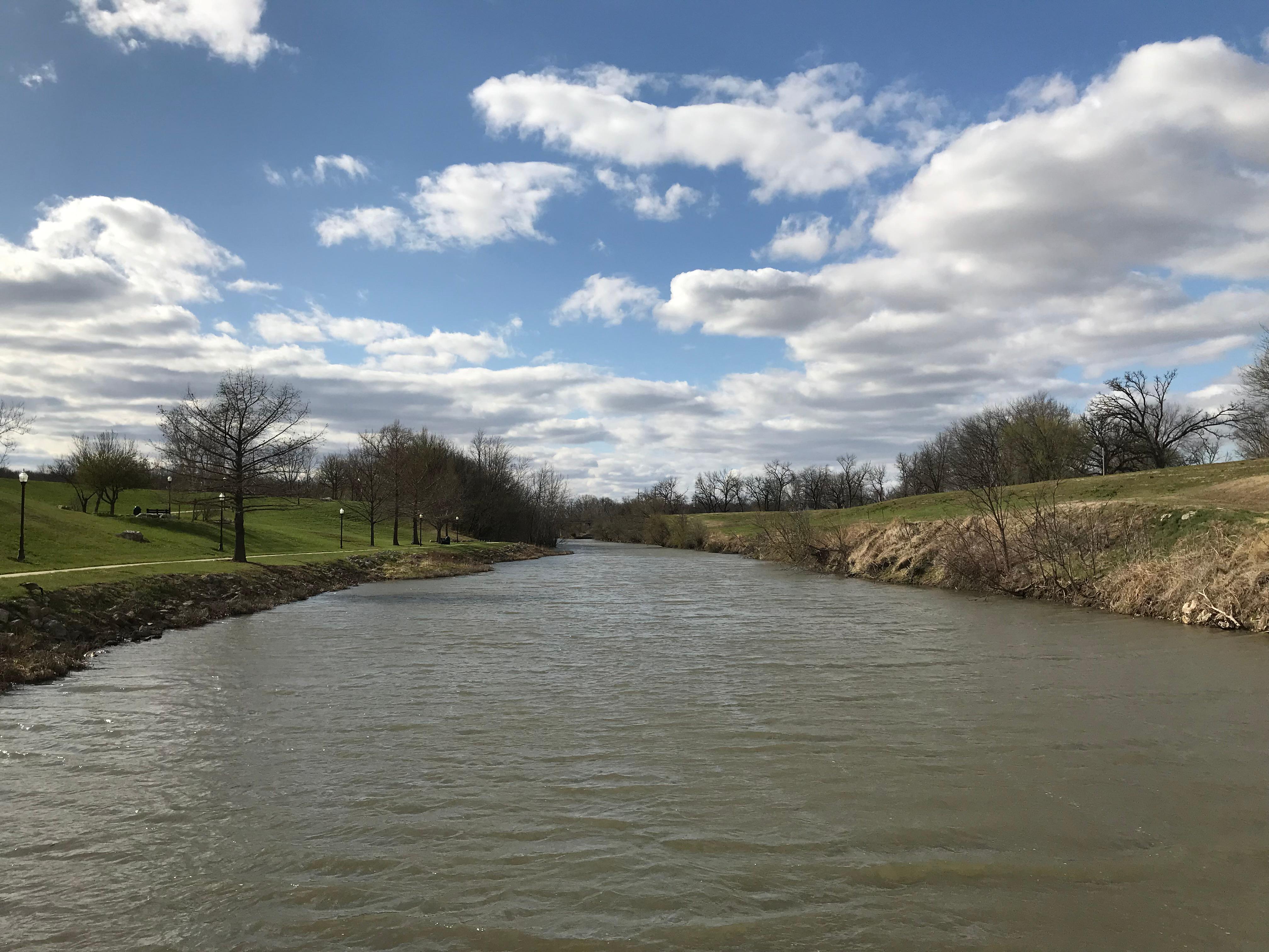 A wide river with green grass parks on the side.