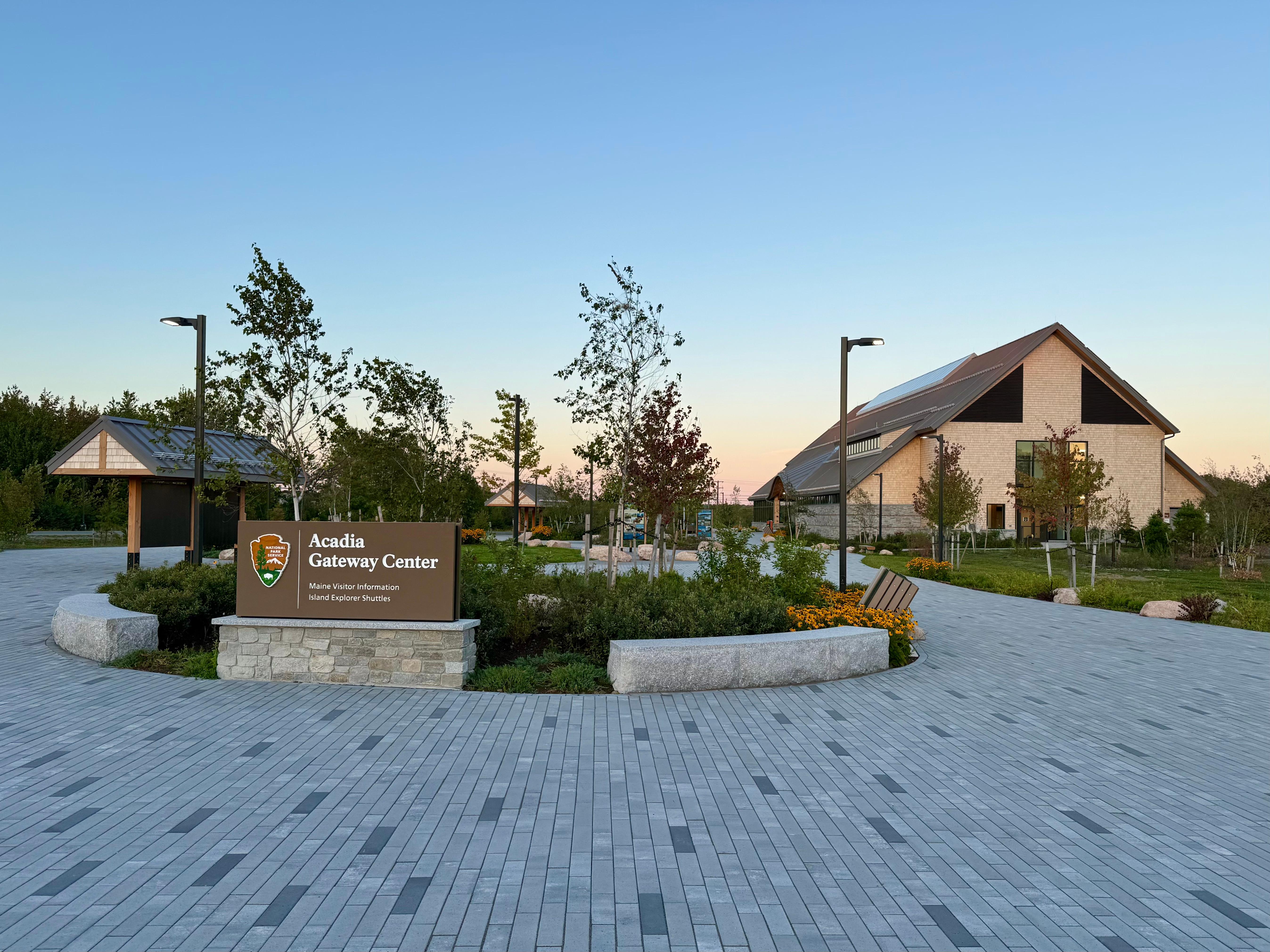 Outdoor courtyard with a circular garden in foreground and visitor center building in the distance