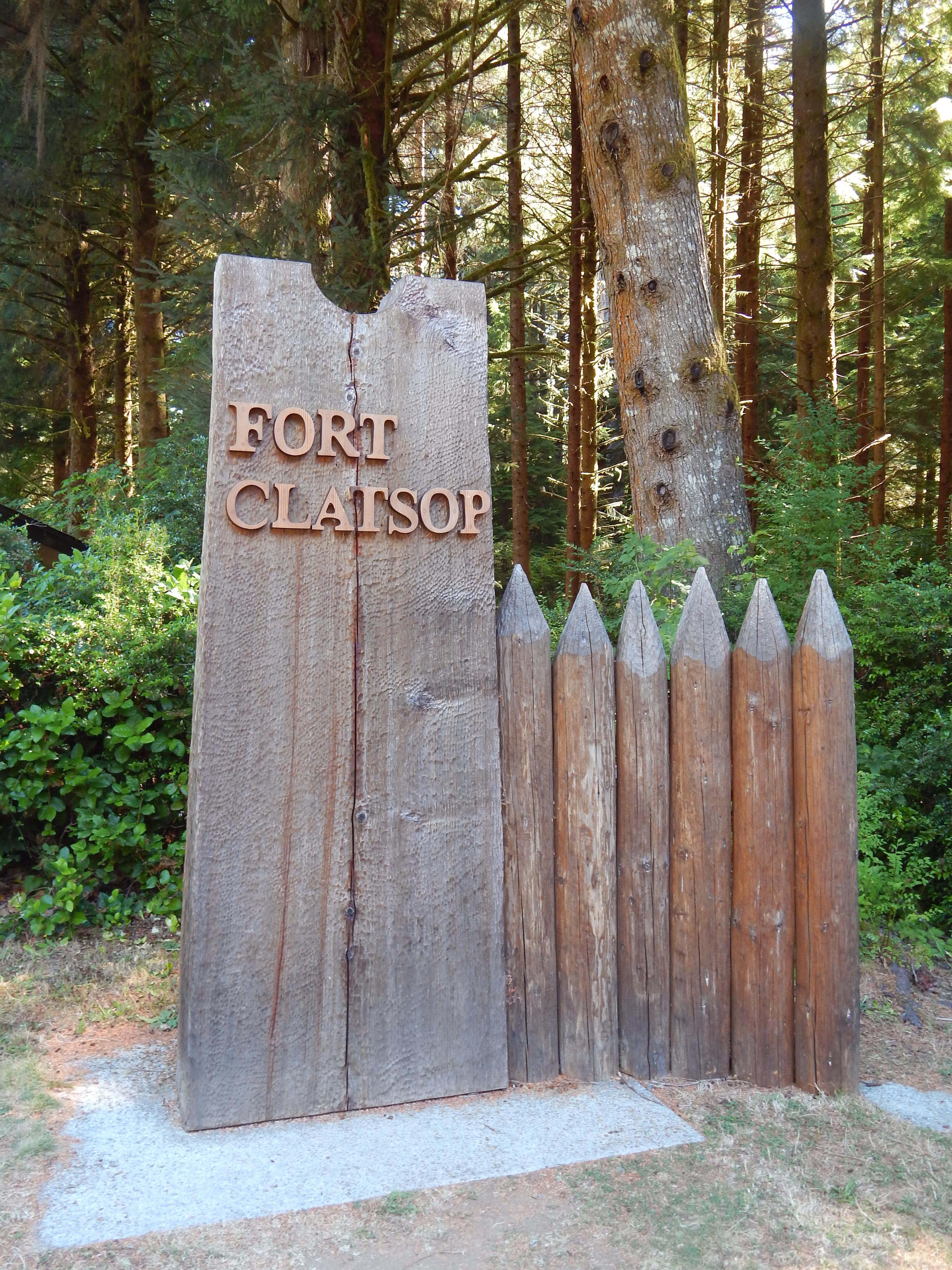 A wooden sign standing as a tall rectangle, the words Fort Clatsop carved of wood placed on it.