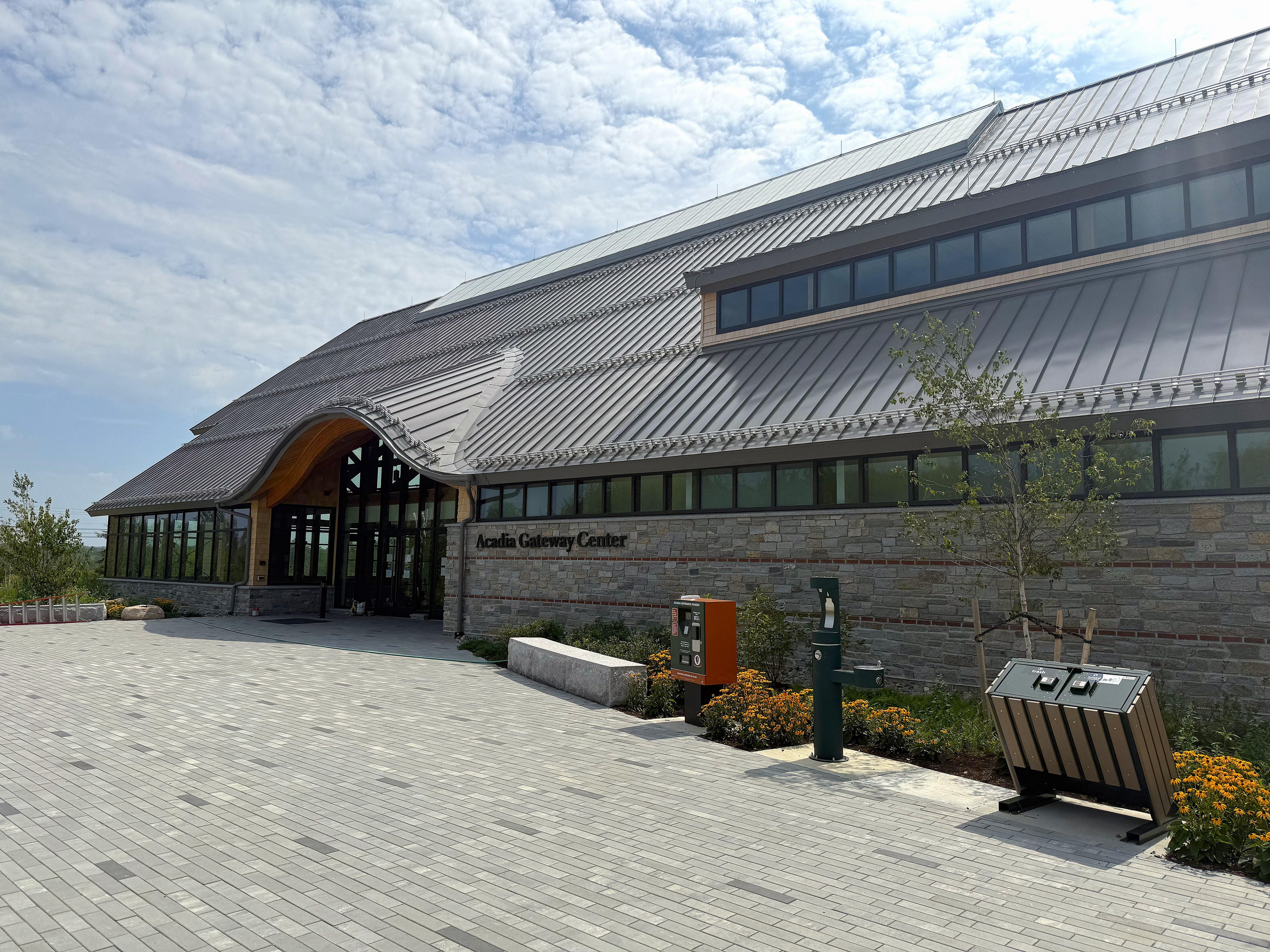 A large building with a metal roof and wide rows of windows and an arched entry way