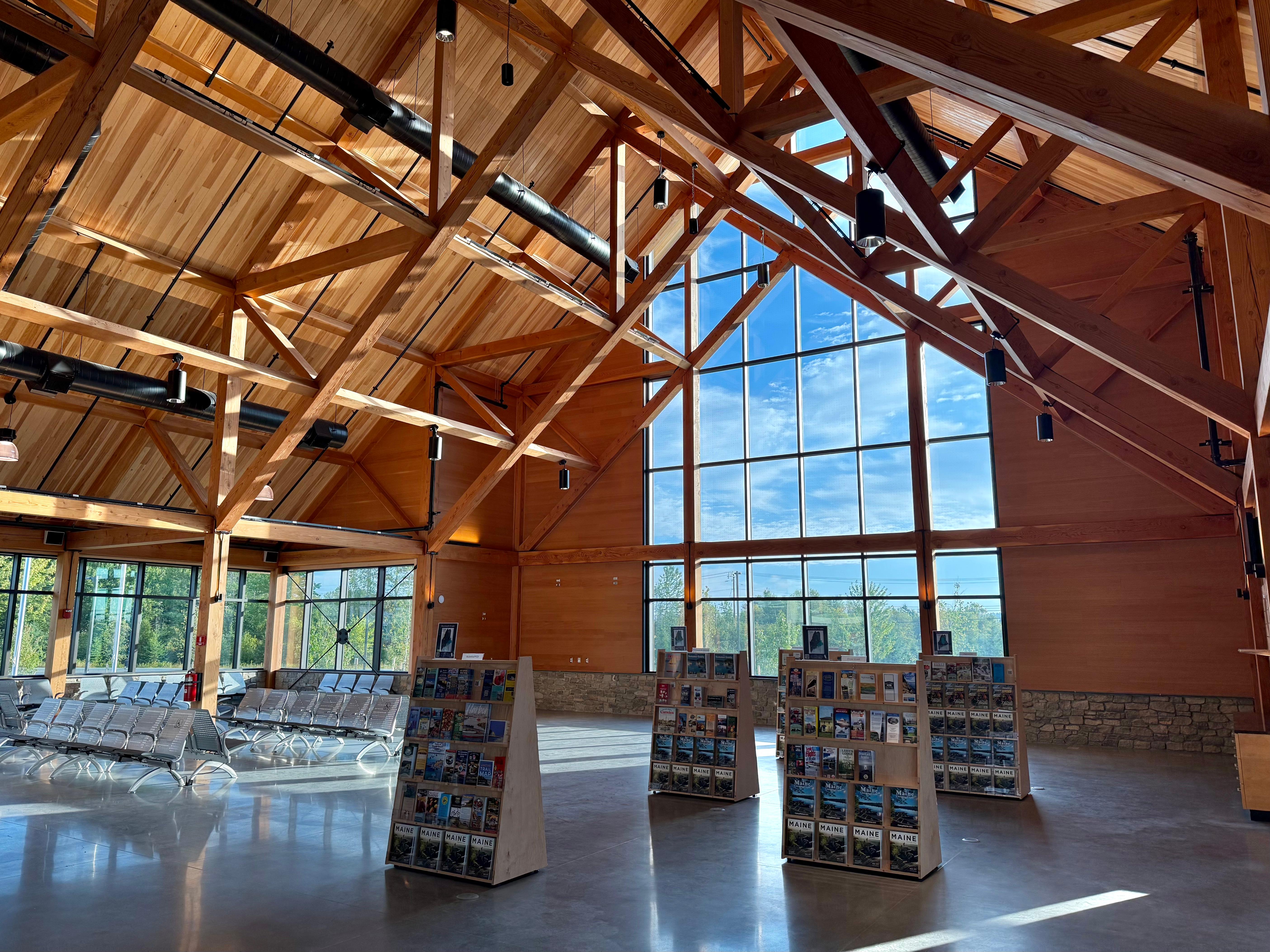 Interior space with high wood beam ceilings, tall windows and rows of chairs for seating