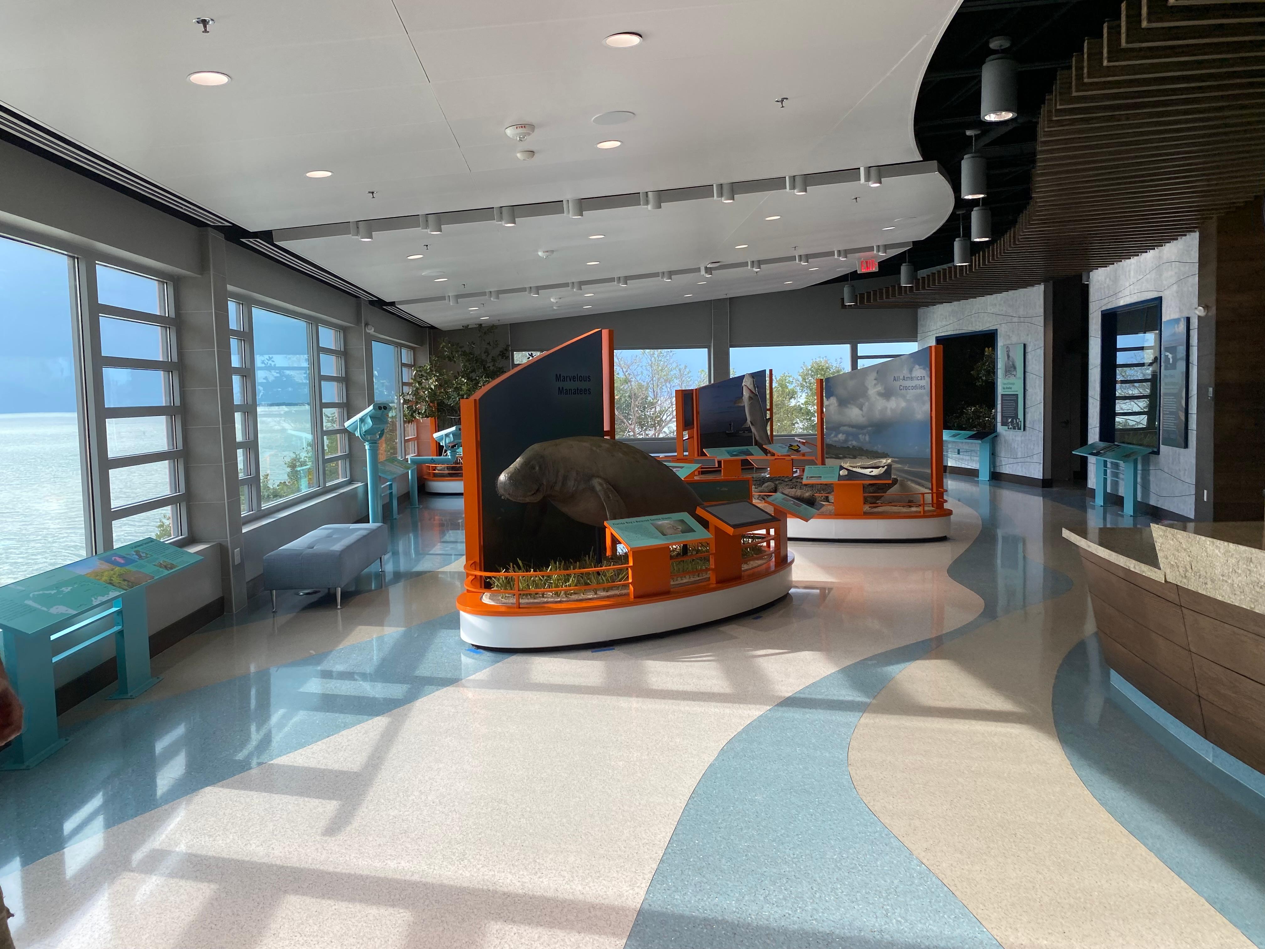 The inside of a visitor center with large exhibits and an ocean view.