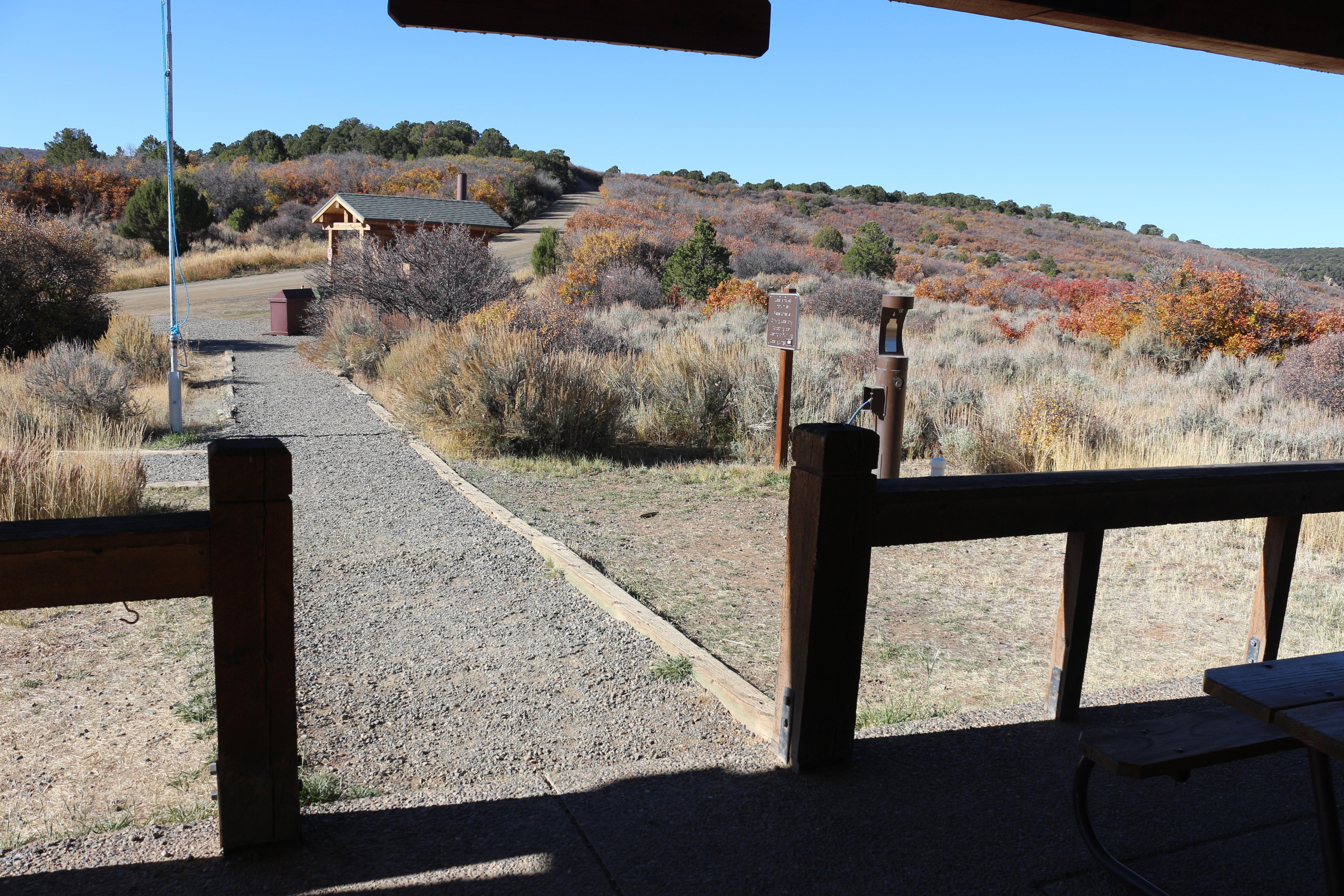 A view from a wooden porch and gravel pathway to a parking lot