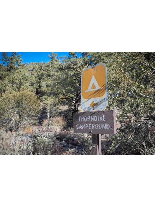 2' metal tent sign on top of small wood horizontal sign on a post reads, Thorndike Campground.