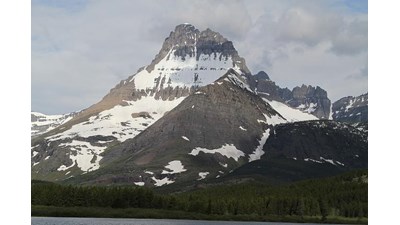 craggy topped mountain rises above forest and lakeshore