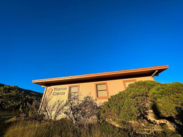A brown building labeled "visitor center" surrounded by green and brown shrubs and grasses