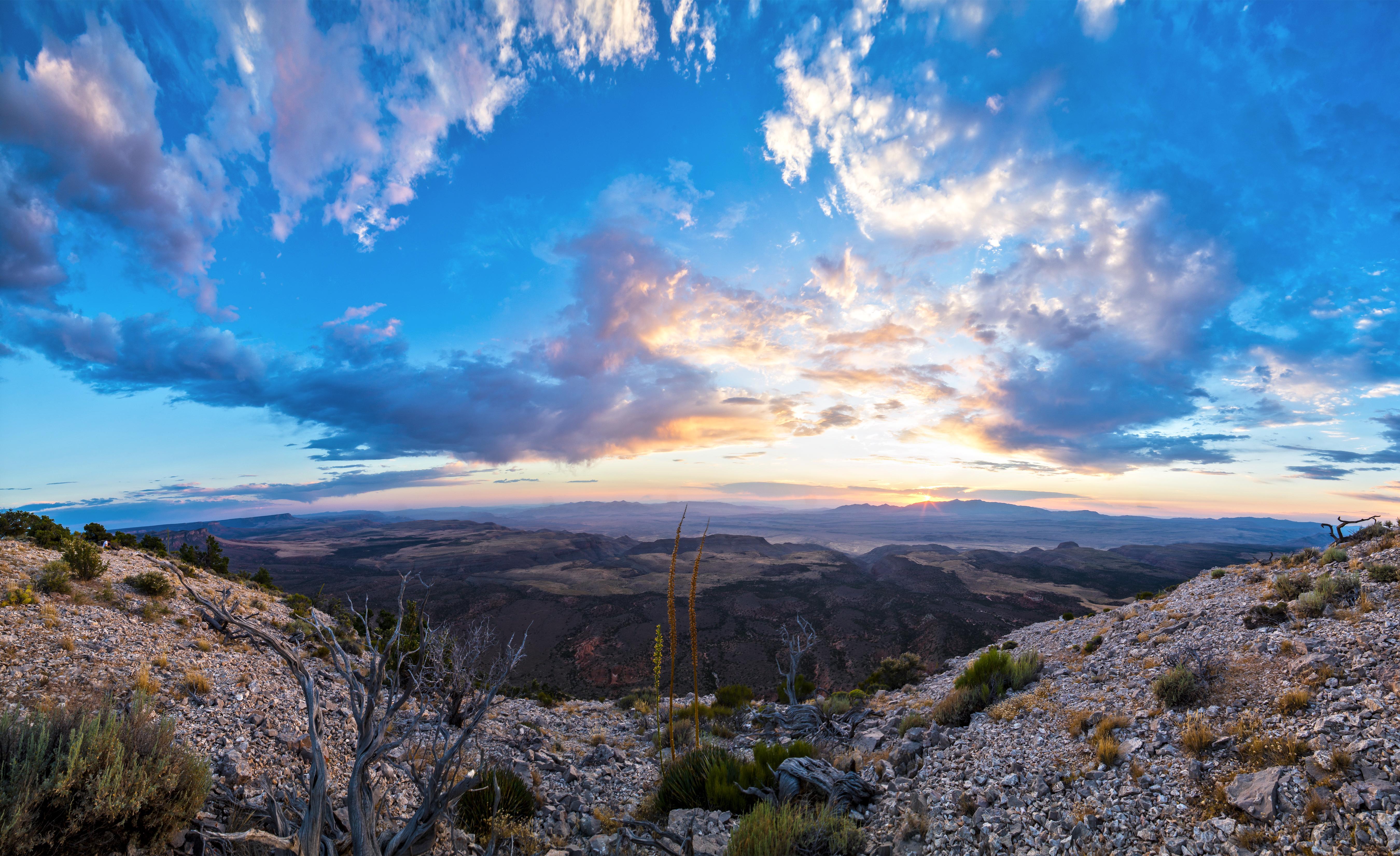 Near a cliff edge the sun sets in the distance.