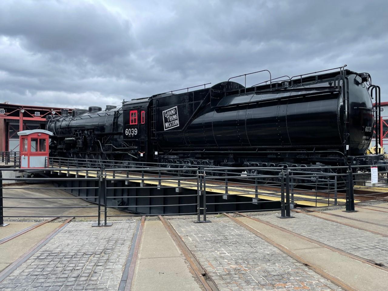large black train with number 6039 painted in white lettering, sitting on turntable track