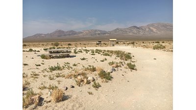 View of the valley, campsite, picnic table and pit toilet from the campground road.