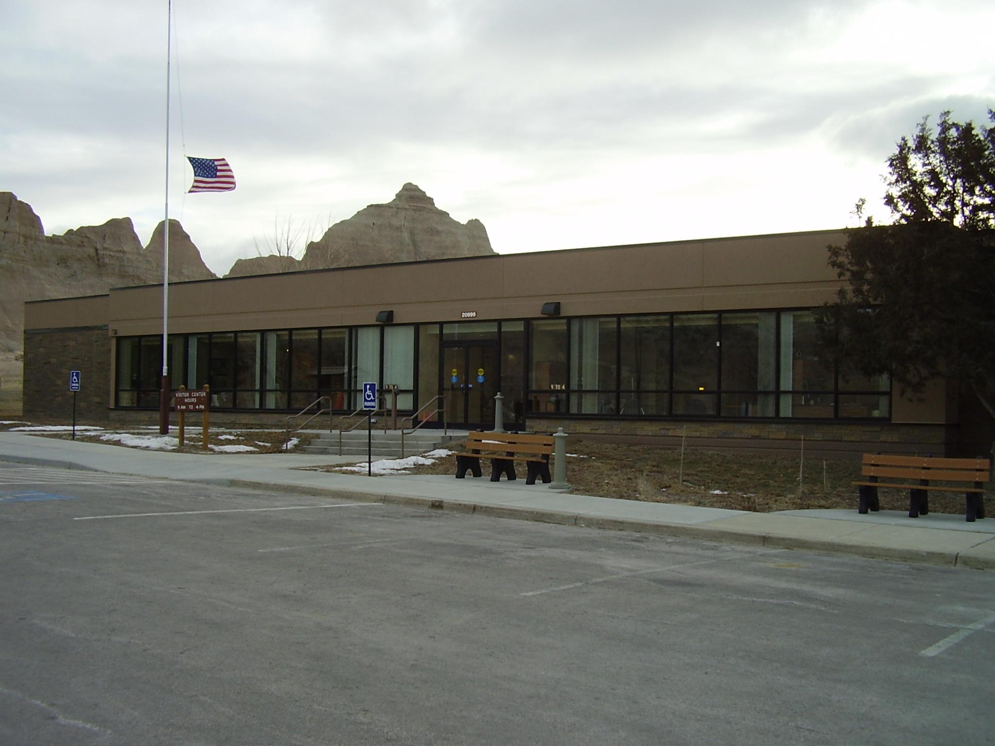 Tan rectangular building under cloudy sky with flag at half mast.