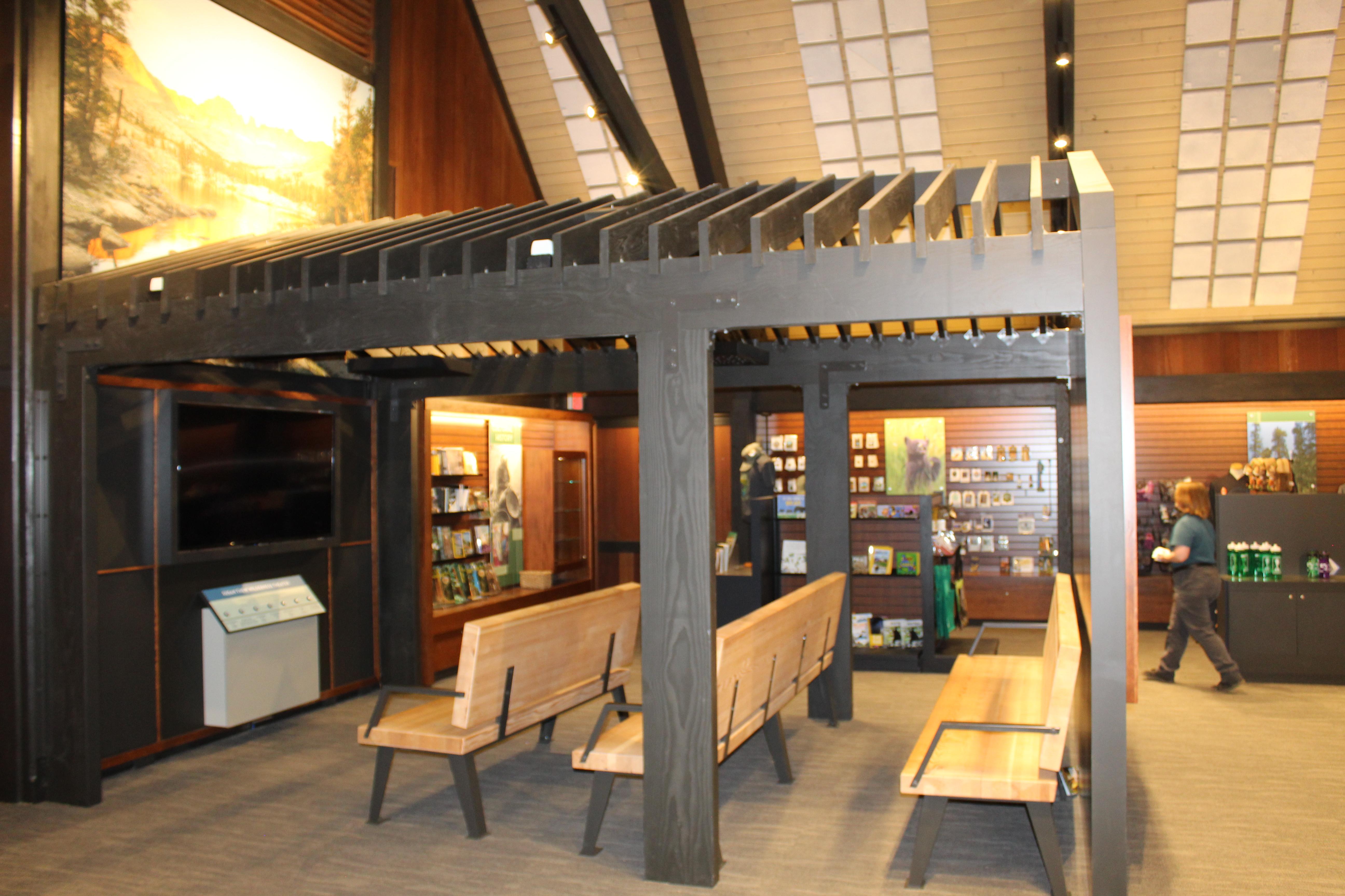 pine benches sit in front of a video monitor