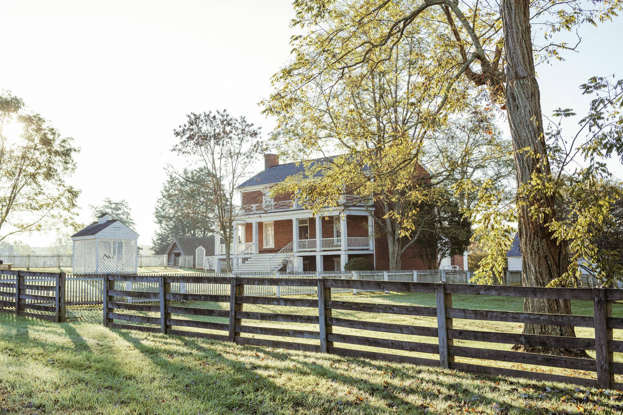 A brick two story home with white pillars and railings.