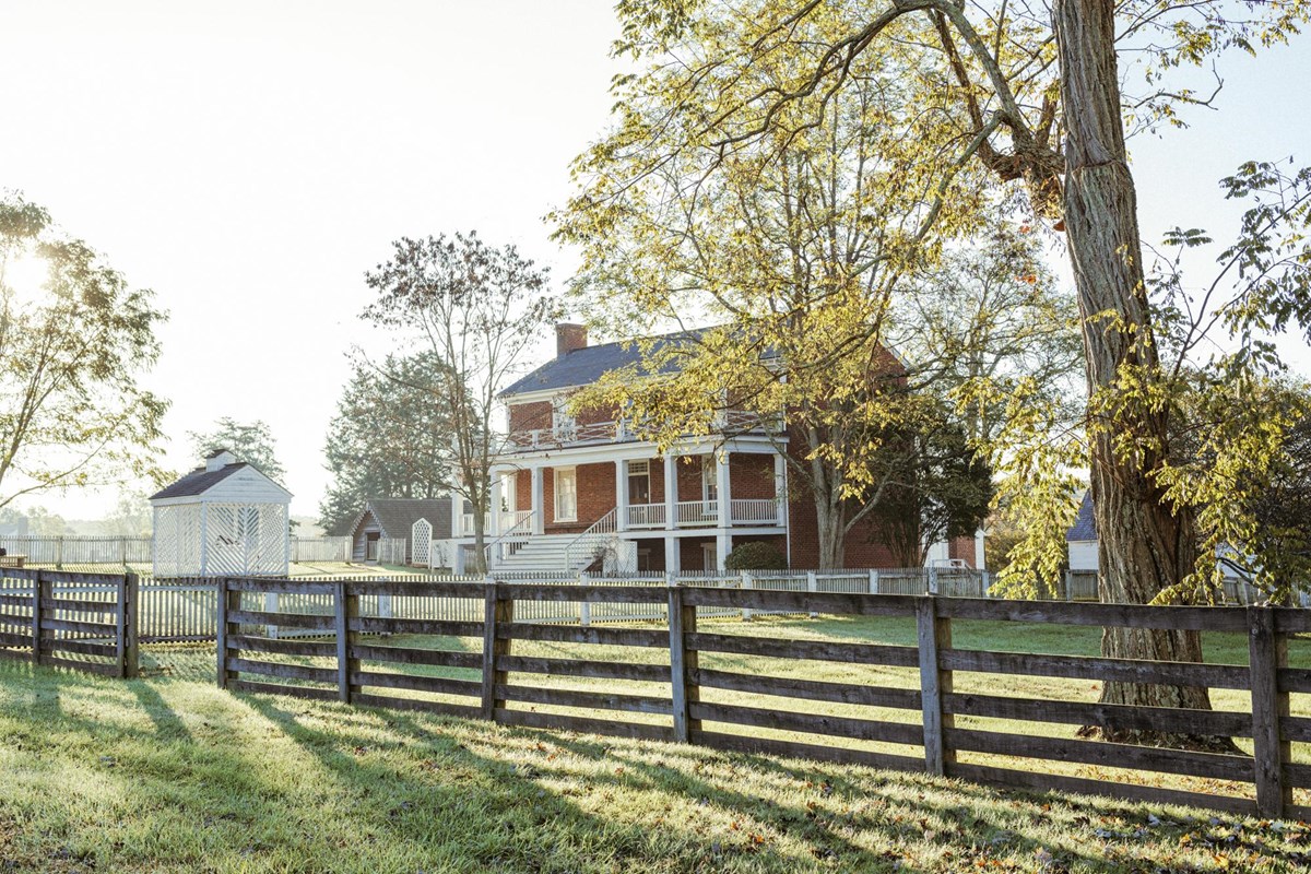 A brick two story home with white pillars and railings.