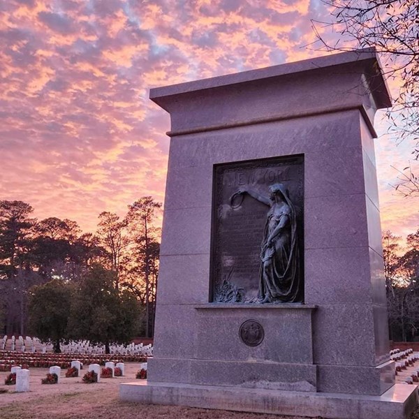 large stone monument with a pink and purple sunset in the background.