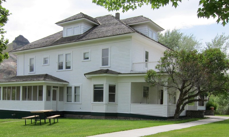 Historic James Cant Ranch Homestead White house surrounded by green with concrete path leading to the front