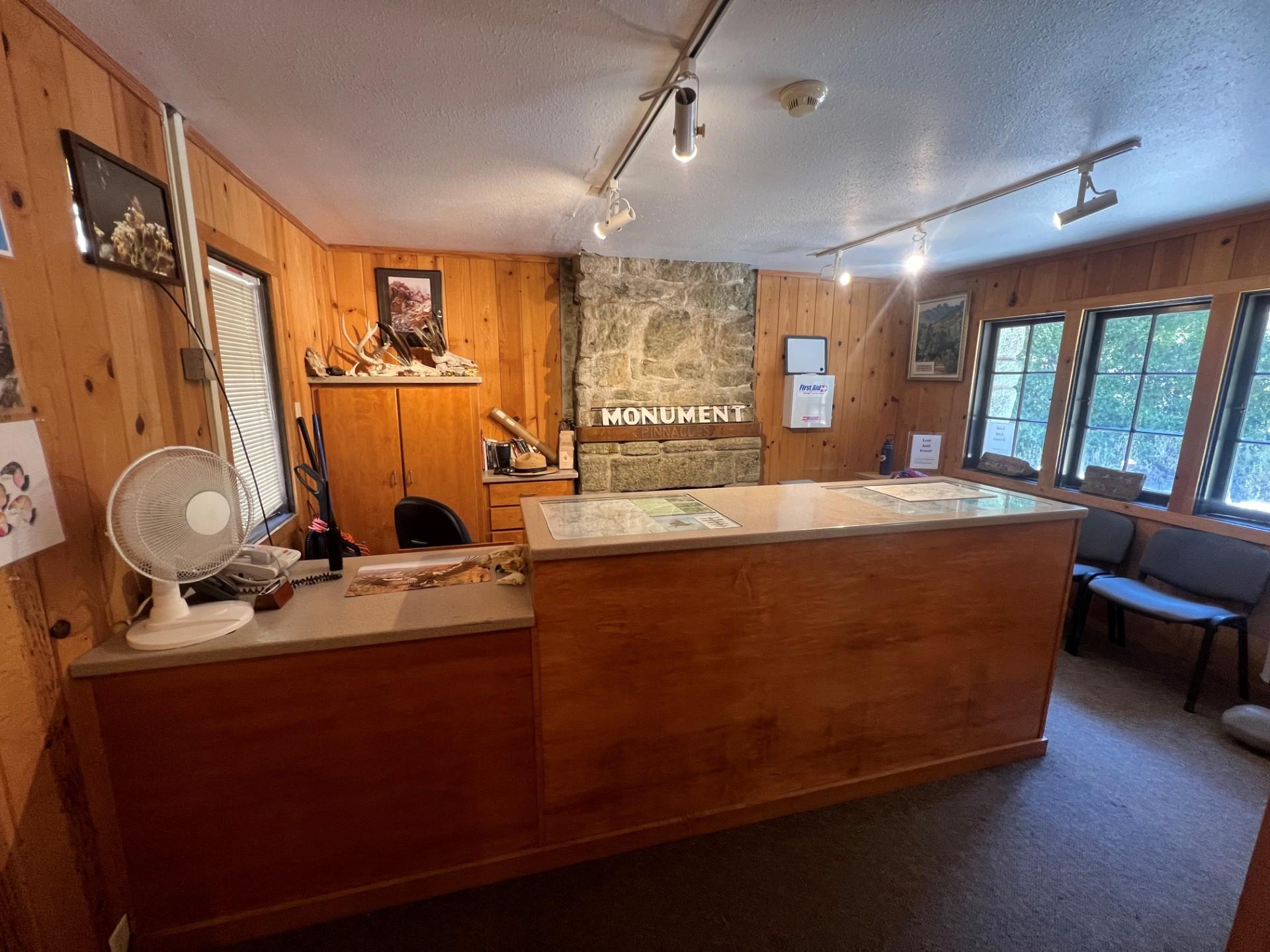Front desk in front of a stone fire chimney inside a small wooden structure