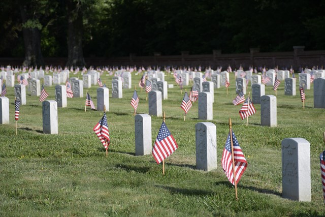 Small American flags flutter in front of white marble headstones.