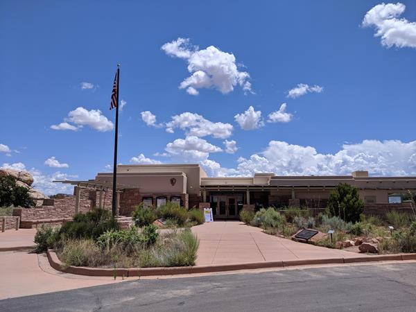 The Needles District Visitor Center plaza, building, and flag pole on a sunny day.