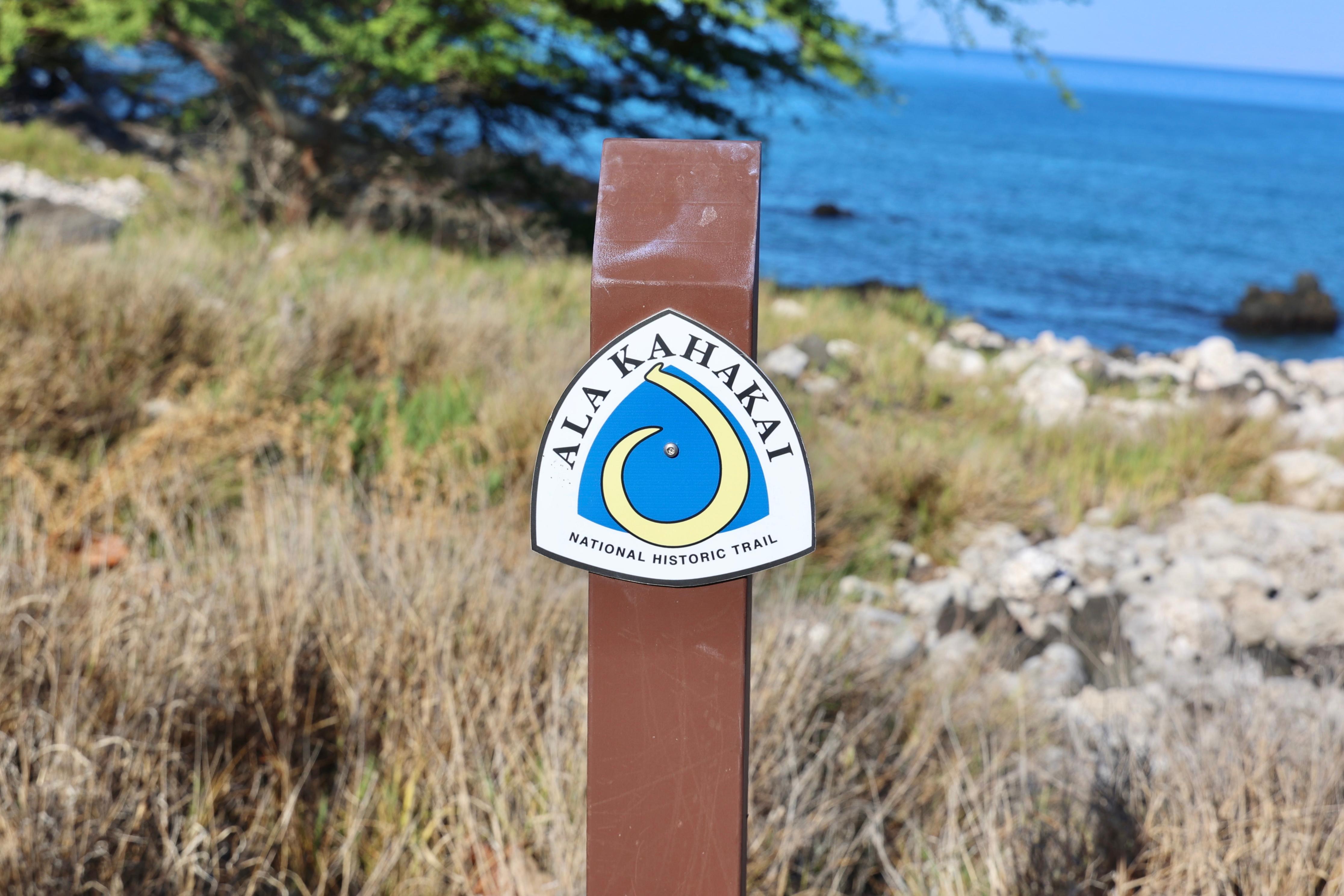 Ala Kahakai trail marker with ocean in the background