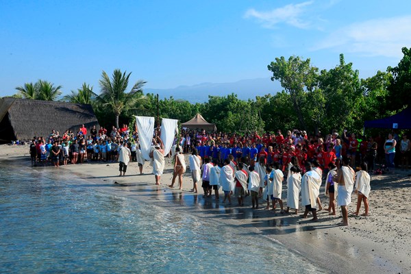 Group of kids form a traditional procession along the beach.