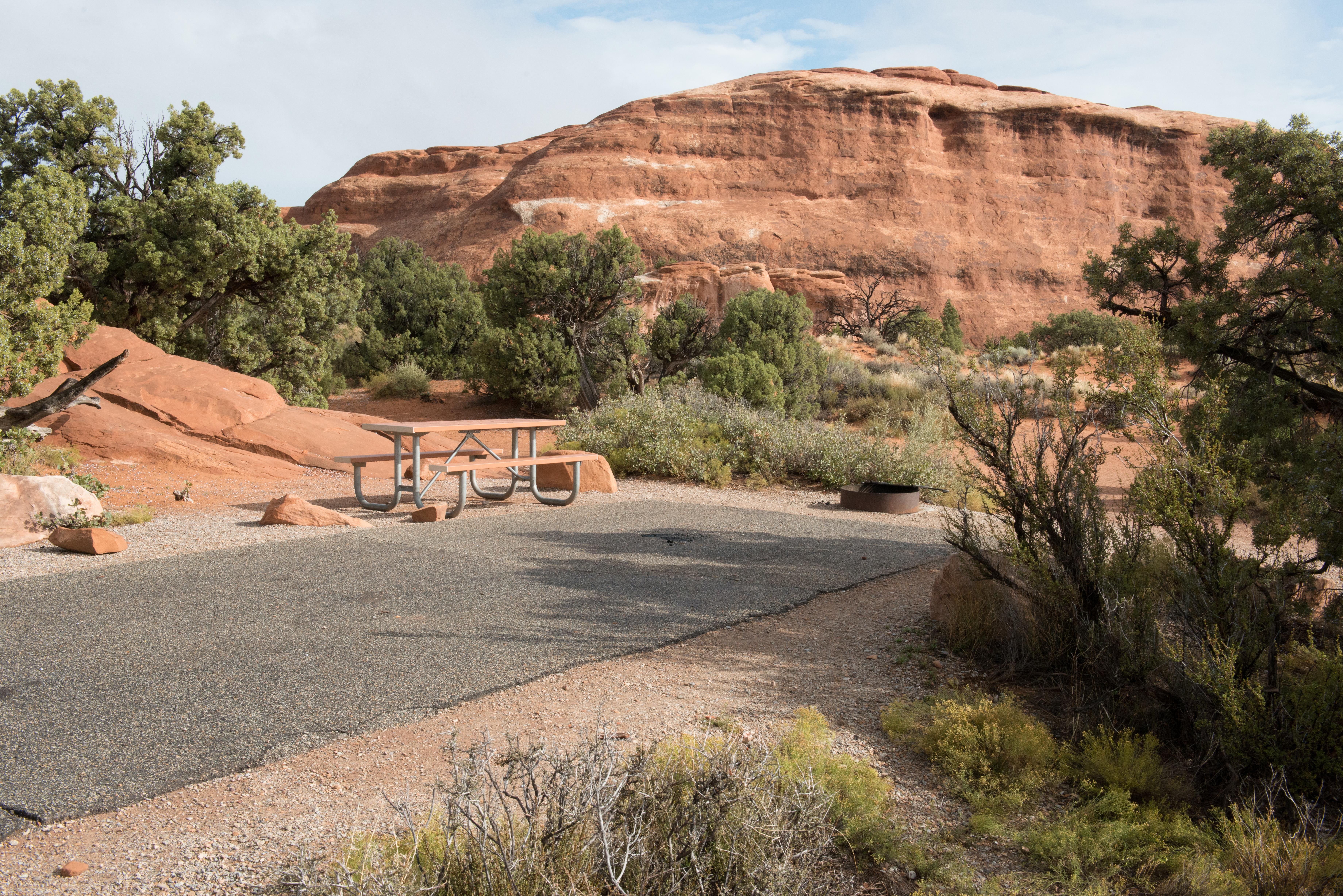 A campsite parking area with rock outcrop above it