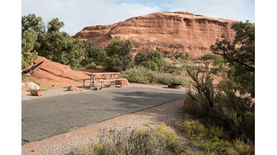 A campsite parking area with rock outcrop above it