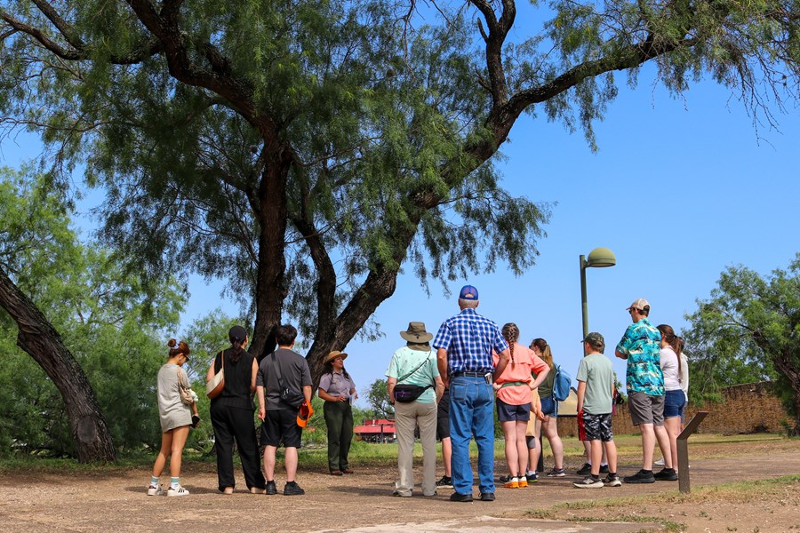 Park Ranger begins a tour through Mission San José under a large mesquite tree