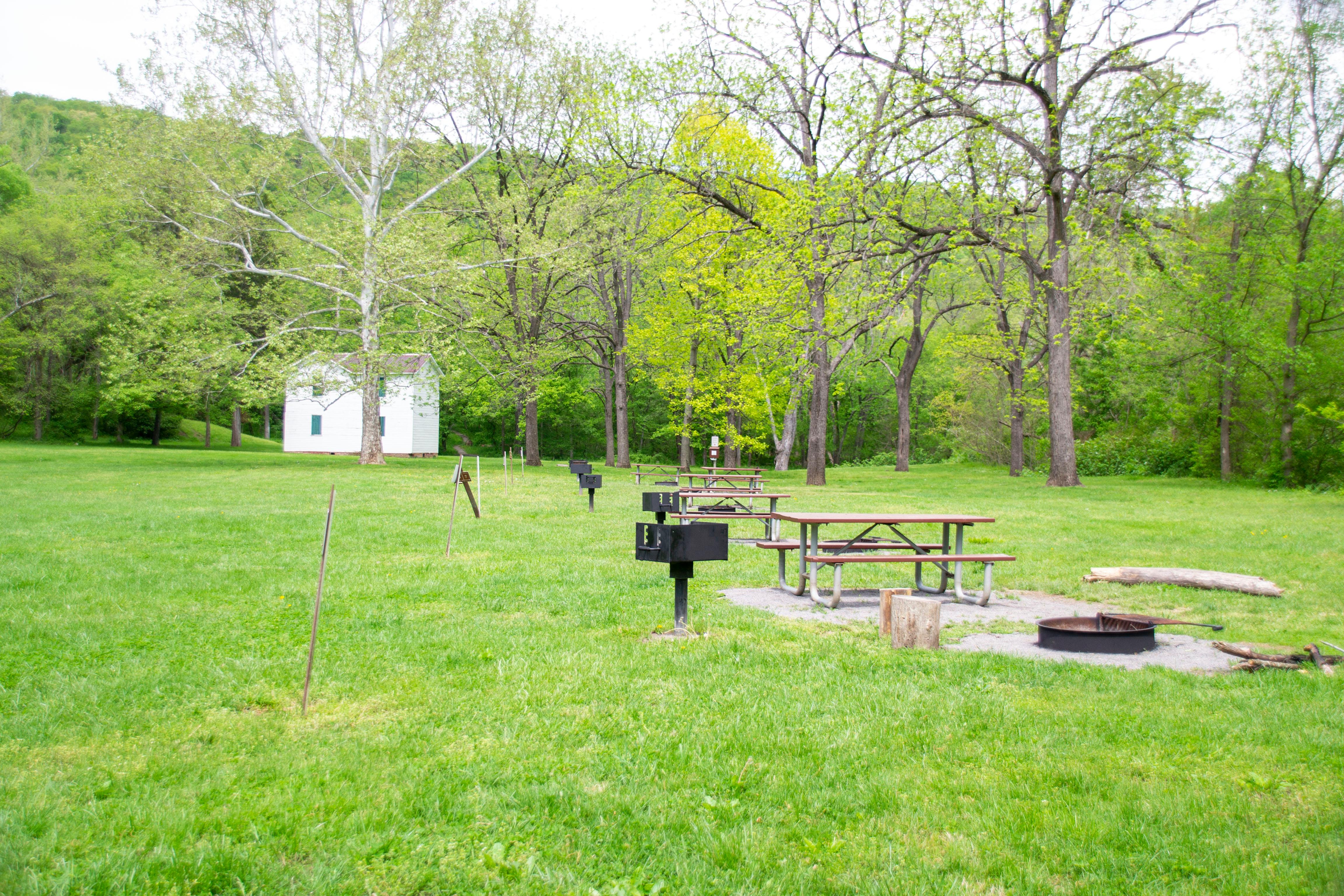 A grassy campsite sits with a lockhouse in the background.