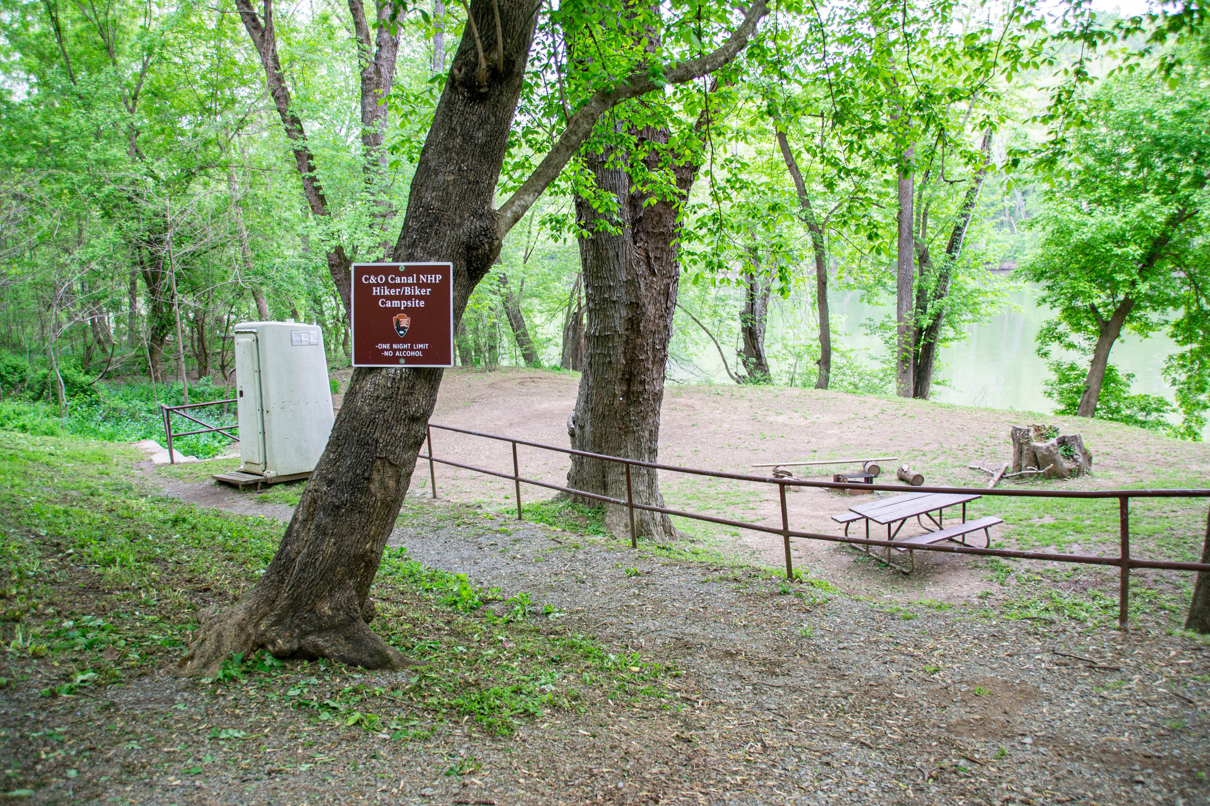 A campsite in the trees surrounded by a fence.