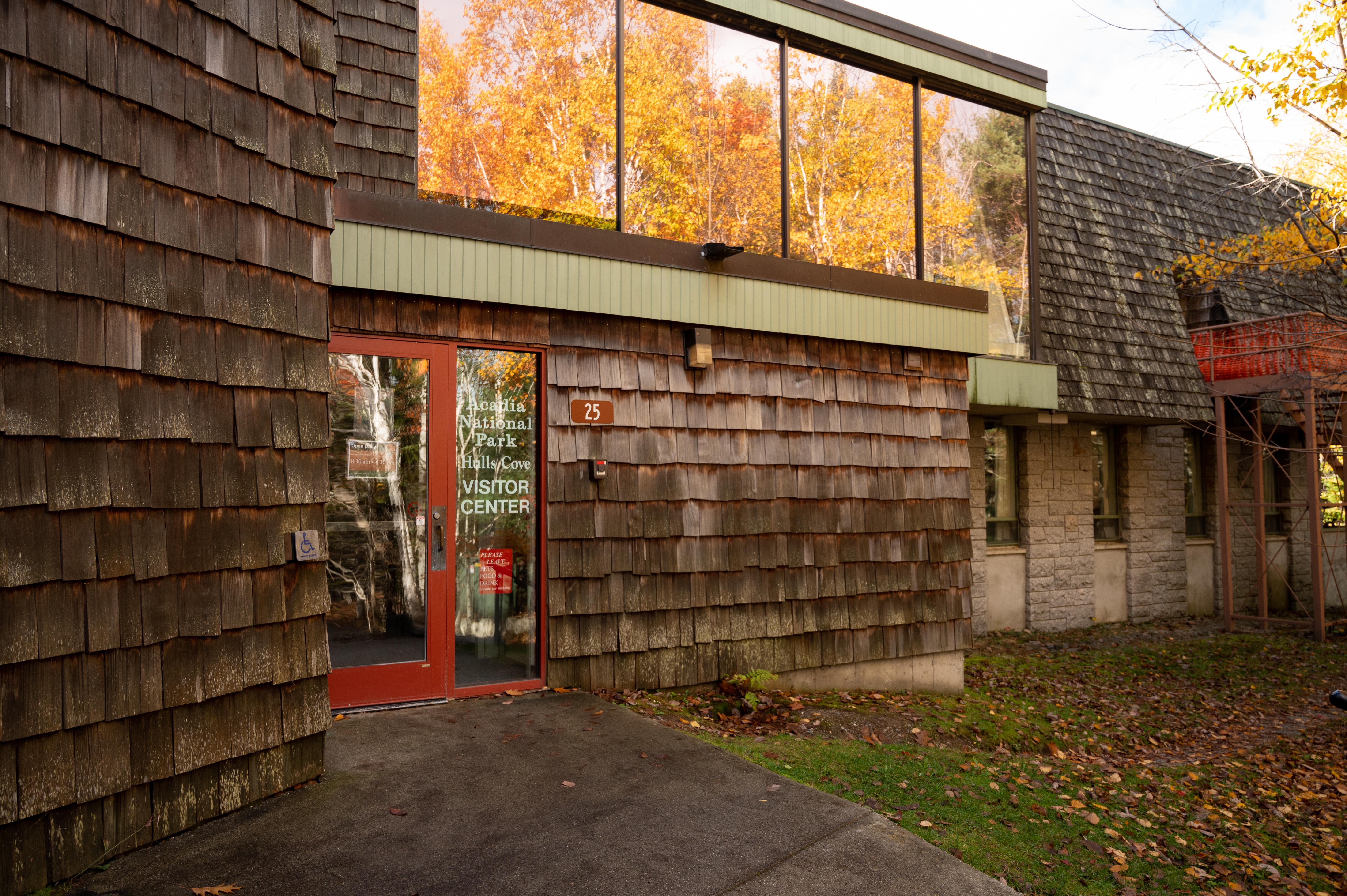 Building exterior covered with cedar shingles and large windows and an entry door at ground level.