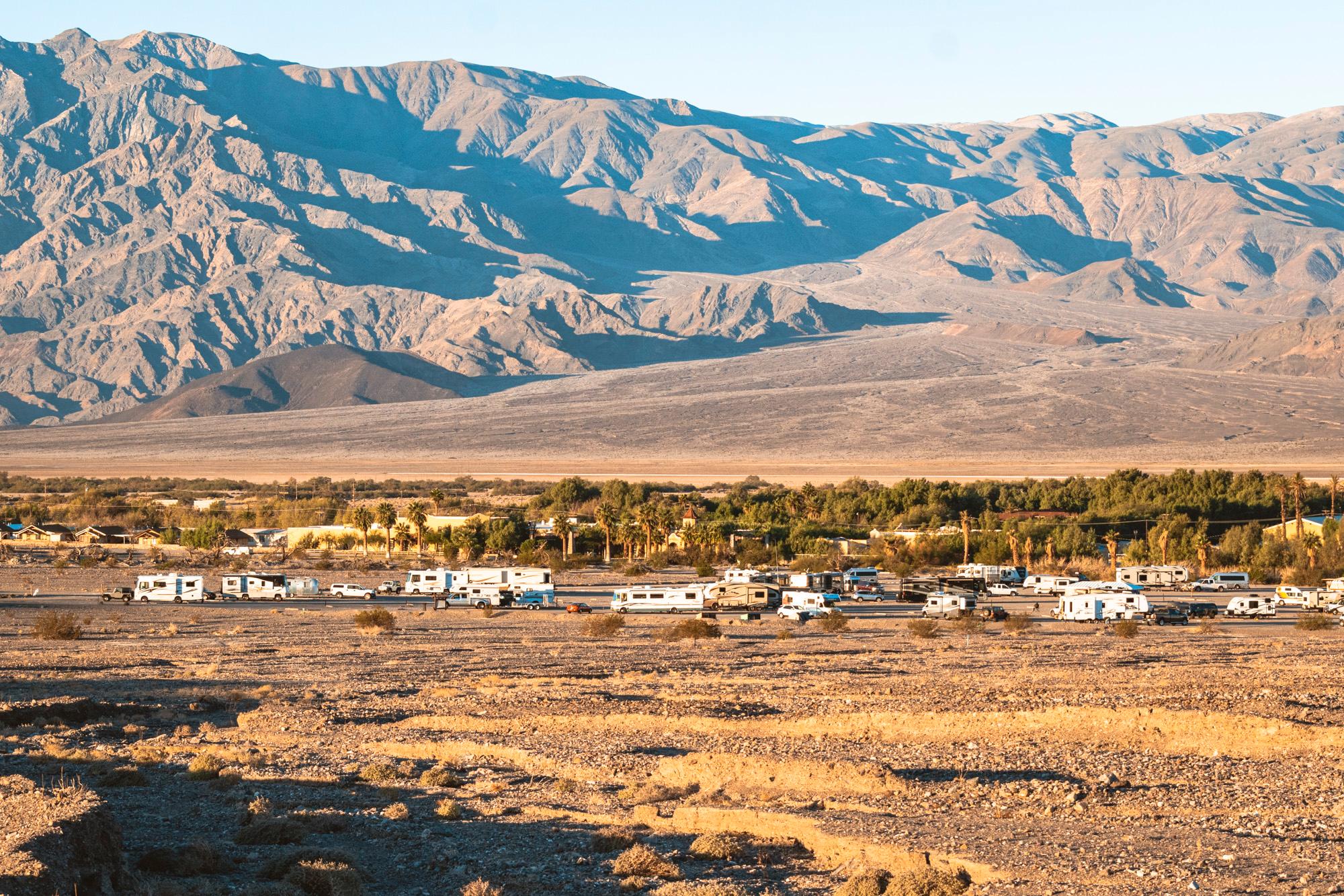 a long distance view of RVs and trailers in a gravel area with distant mountains