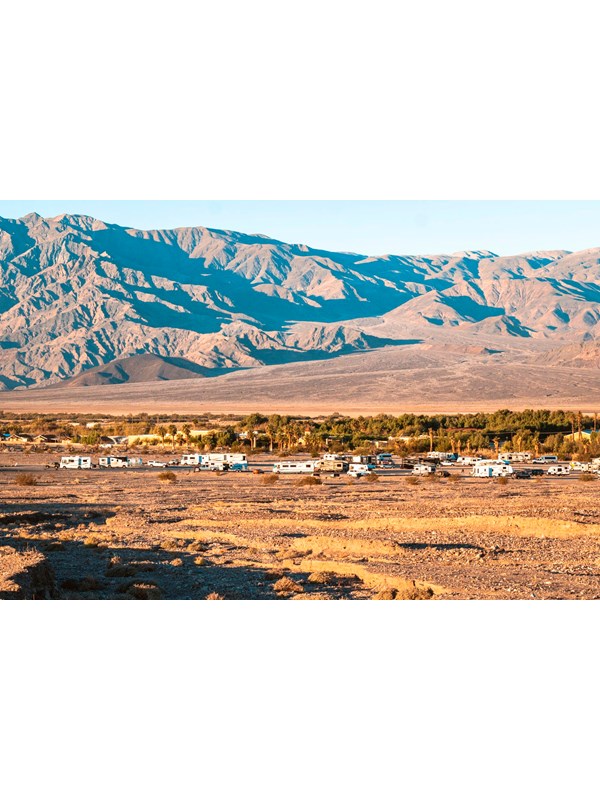 a long distance view of RVs and trailers in a gravel area with distant mountains