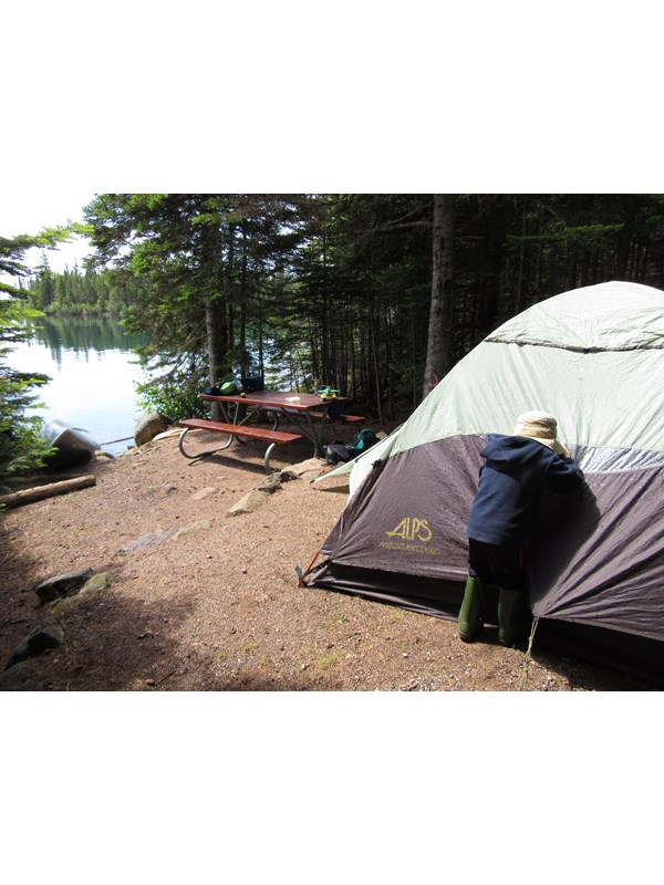 A child pressed against a tent on the edge of Lake Superior.