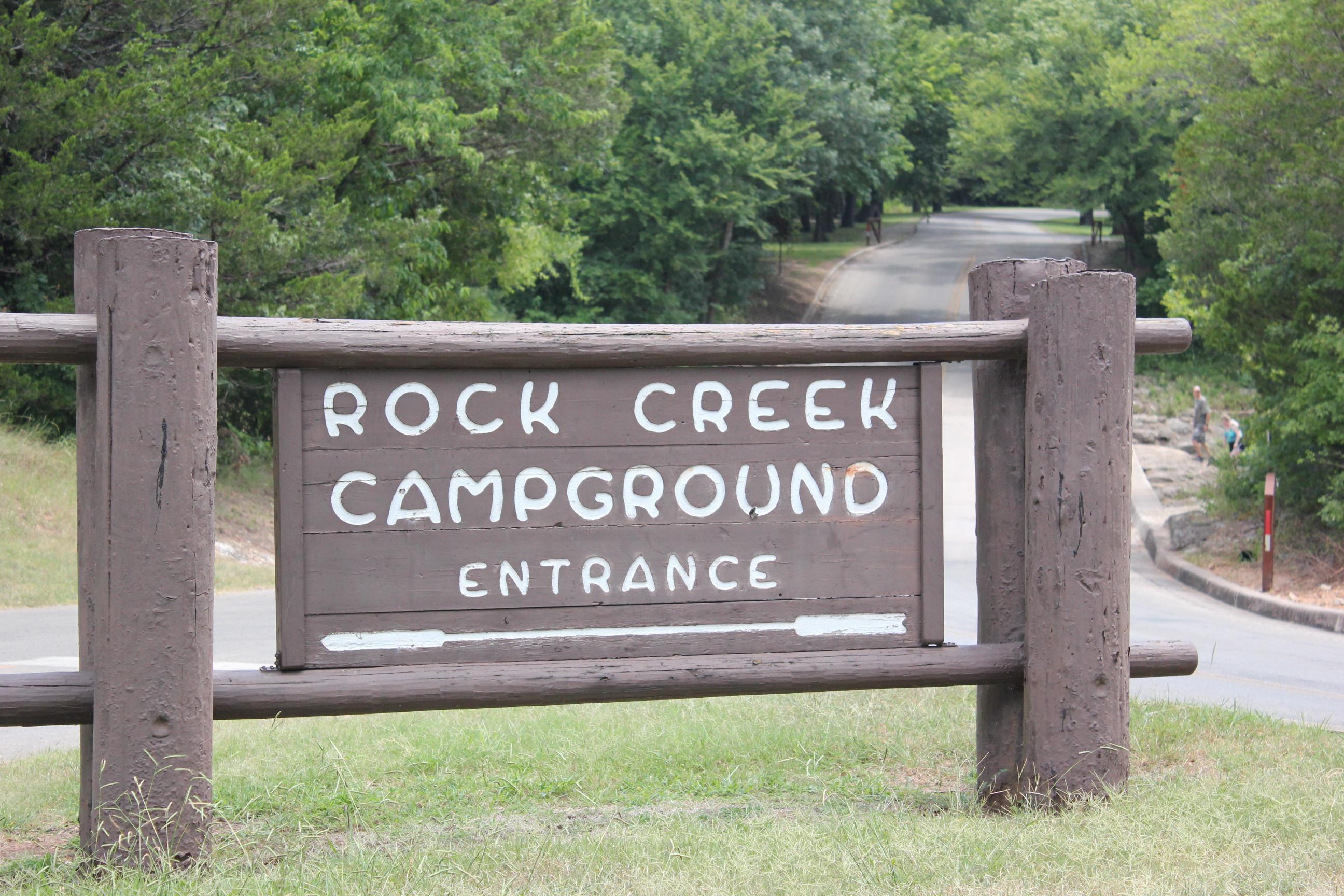 A large, old style wood sign with white lettering states "Rock Creek Campground Entrance"