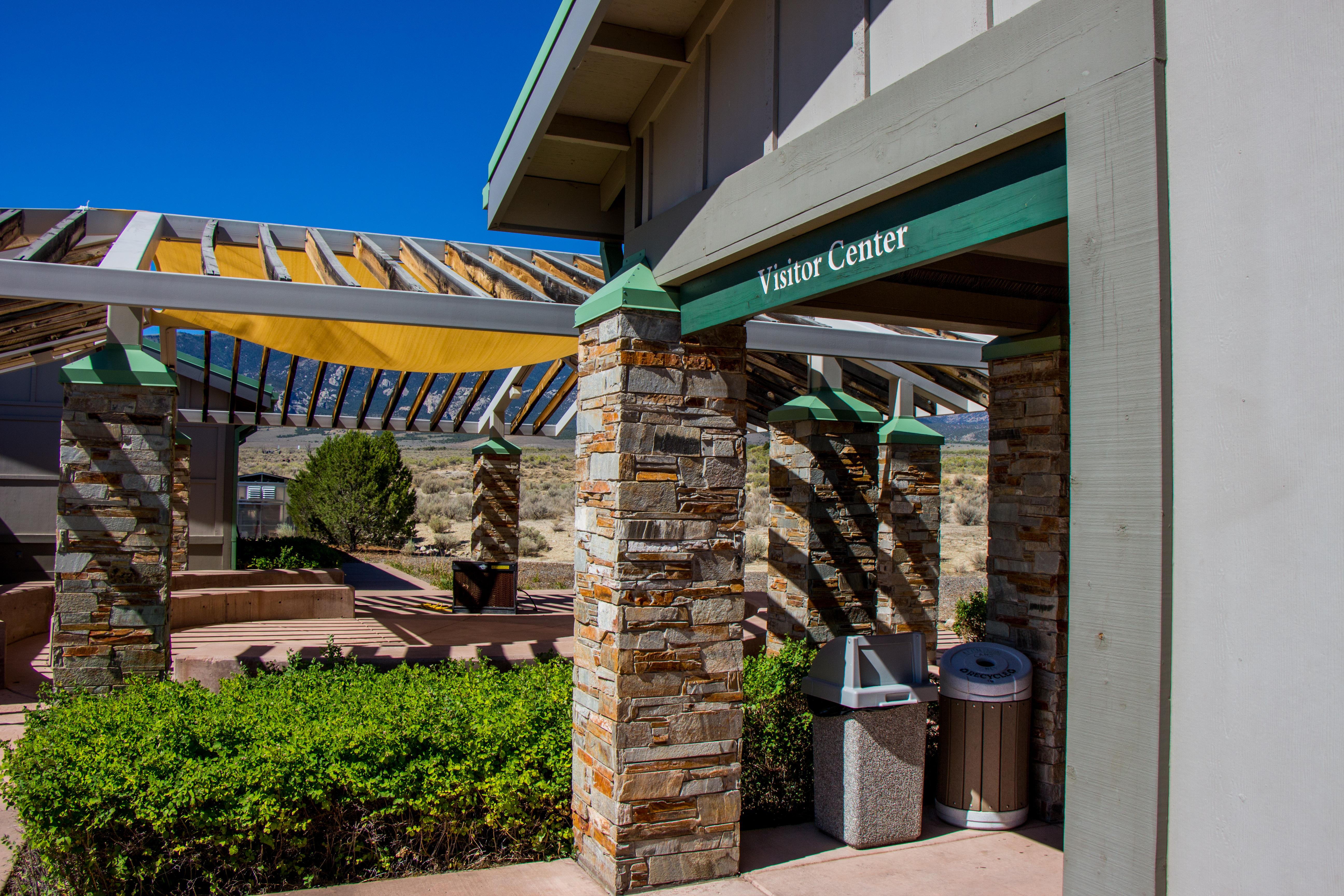 Tan and green Visitor center with mountains in the background.