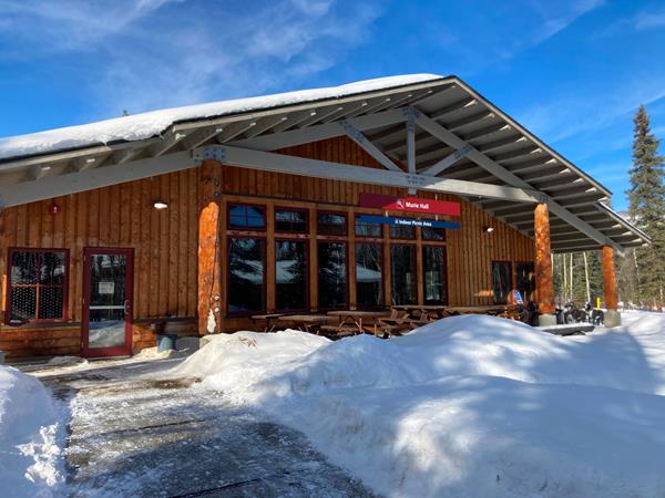 Wooden building surrounded by snow, with a sign that reads "Murie Hall, Indoor Picnic Area"