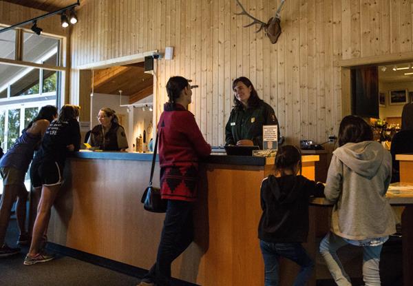 Visitors chat with a ranger at a desk inside a visitor center.