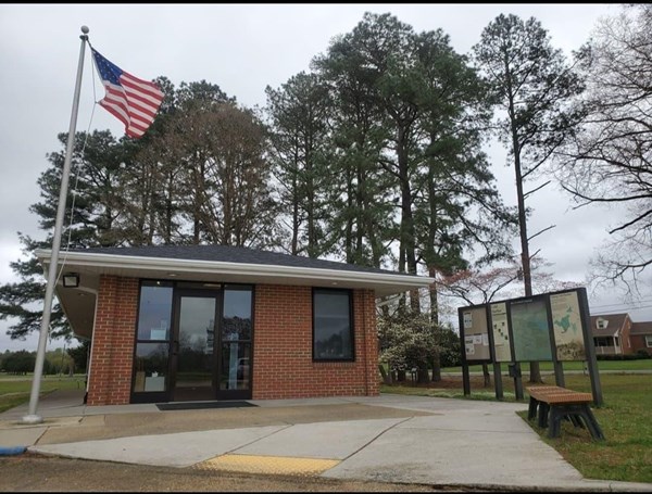 A small brick visitor center building beside a flagpole.