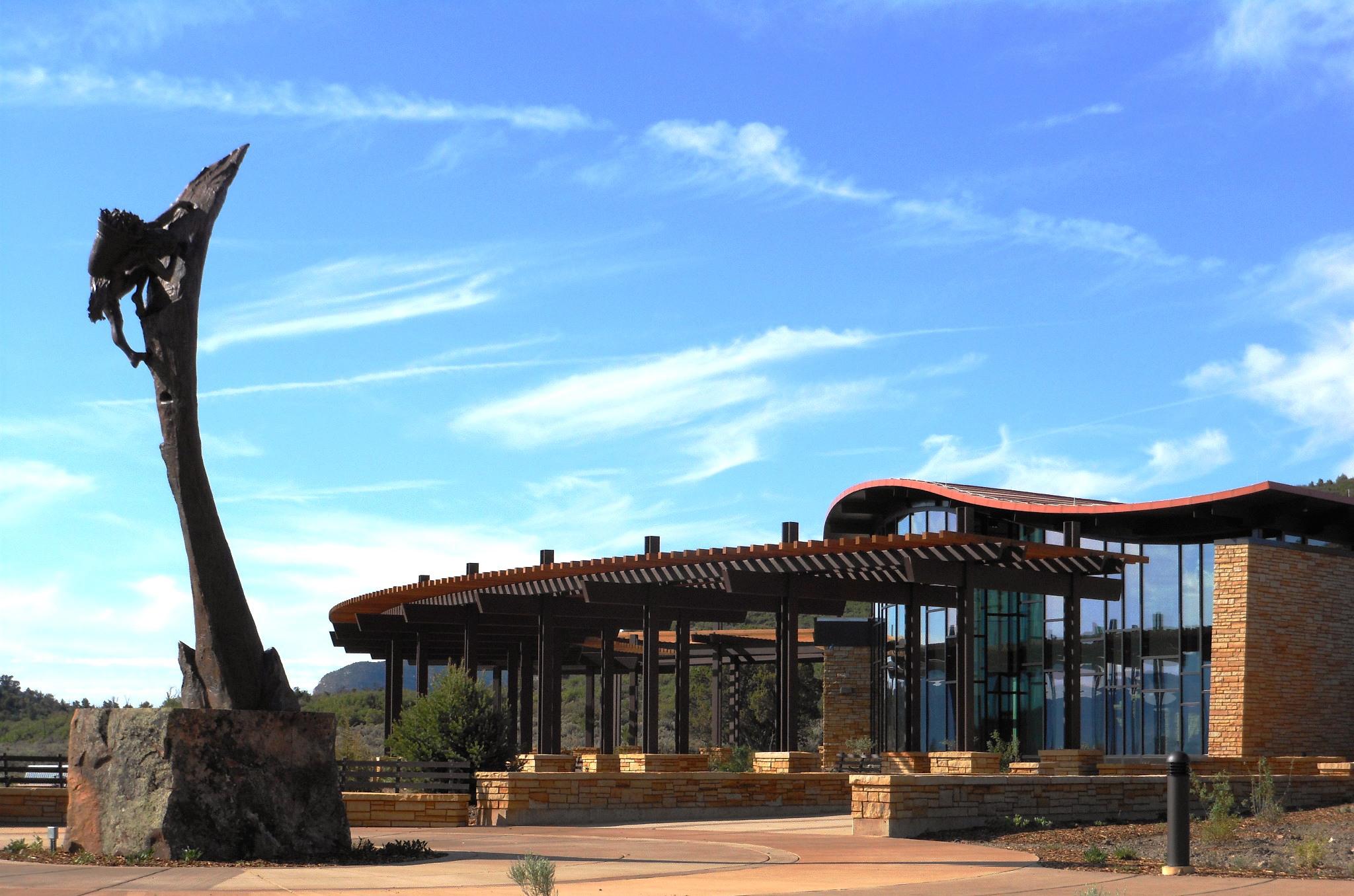 Visitor center entrance with sculpture of Ancestral Pueblo climber in front plaza.