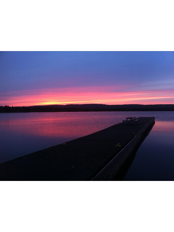 Sunset on the horizon of Siskiwit Bay, Lake Superior with a dock stretching into the water