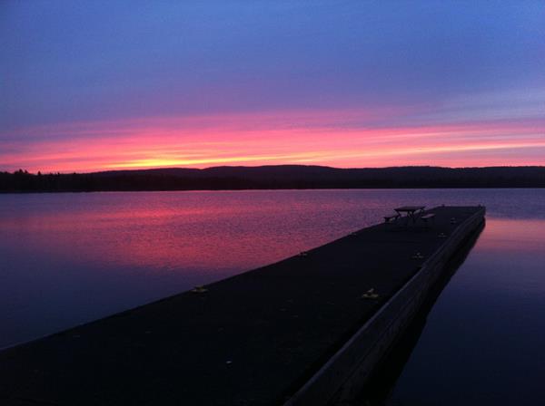 Sunset on the horizon of Siskiwit Bay, Lake Superior with a dock stretching into the water